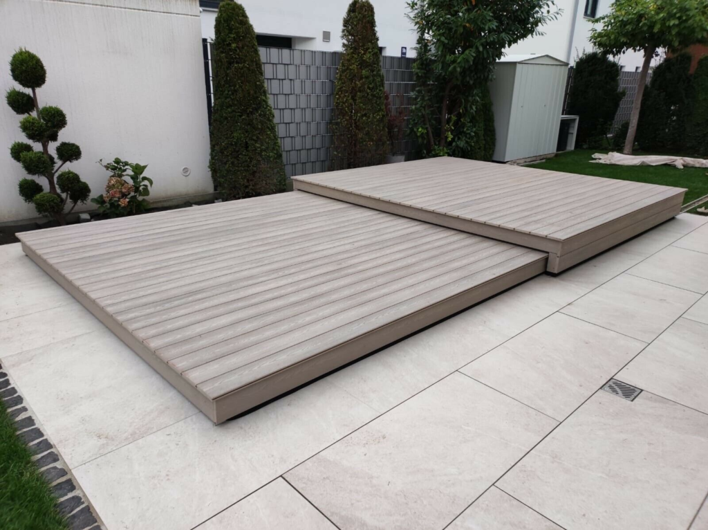 Ein graues begehbares Pooldeck in 2 Stufen in einem Garten