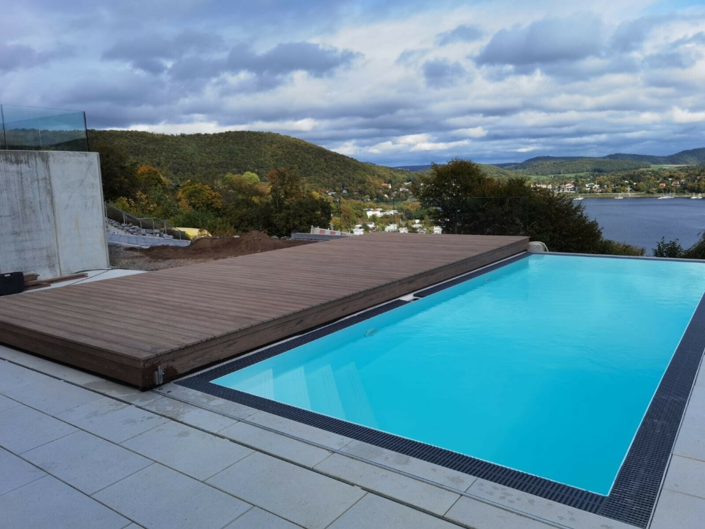 Pool mit offenem Pooldeck mit Aussicht auf einen See unter blauem Himmel