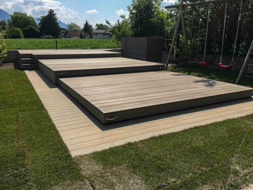 Funktionales und ansprechendes Pooldeck von Terrassen Design Riegler, das eine große Grünfläche ergänzt und den Außenbereich vielseitig nutzbar macht.