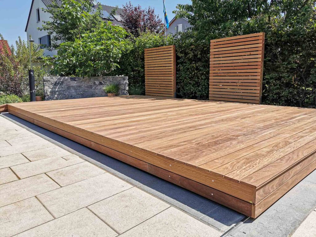 Hochwertige begehbare Poolabdeckung aus Holz von Terrassen Design Riegler, harmonisch integriert in einen modernen Garten.